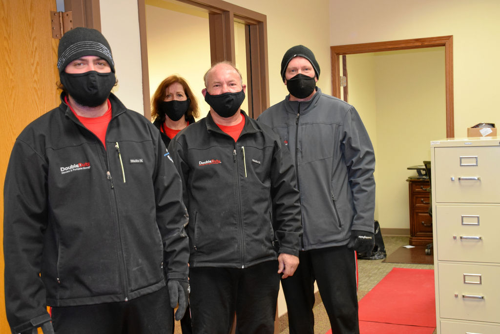 A group of people wearing masks and standing in front of a door.
