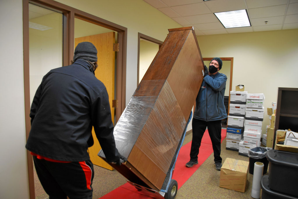 Two men moving a large piece of furniture.