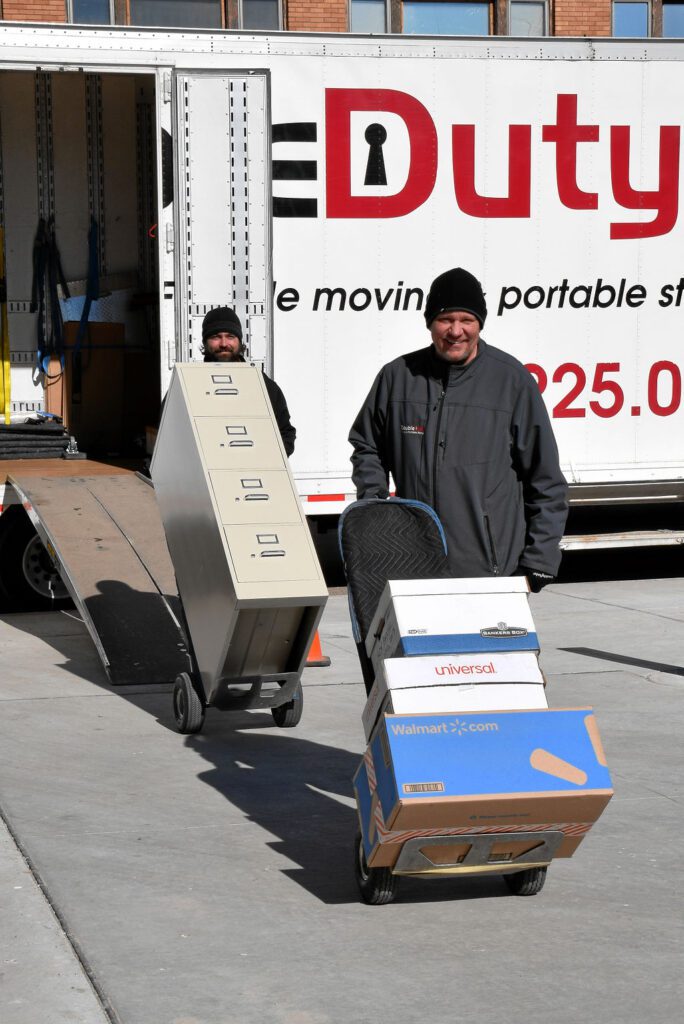 Two men moving furniture in front of a truck.