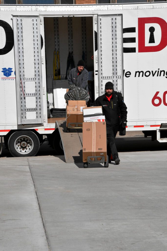 Two men unloading boxes from a moving truck.